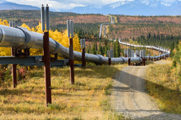Long pipeline stretching across a scenic landscape with autumn foliage and distant mountains.